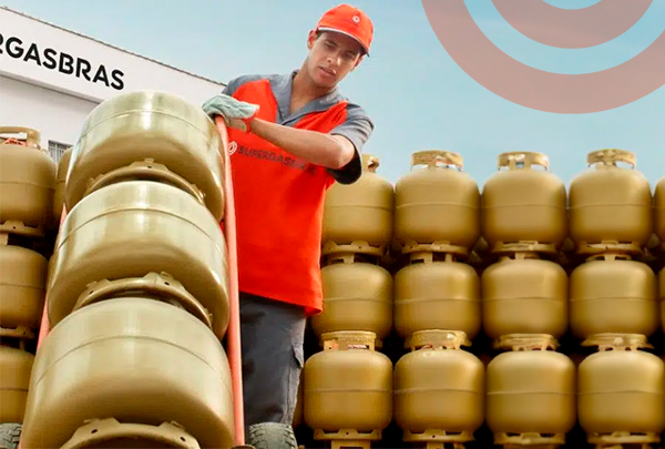 homem manuseando botijão de gás dourado ao fundo fachada da supergasbras